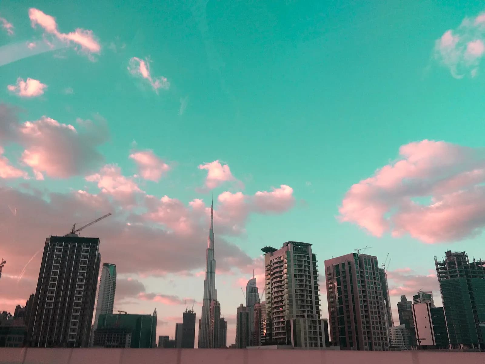 Office towers in Dubai's Business Bay district with the Burj Khalifa rising behind them at dusk