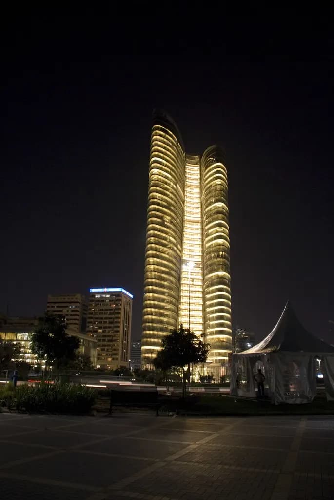 Curved office tower lit up at night on the Abu Dhabi corniche