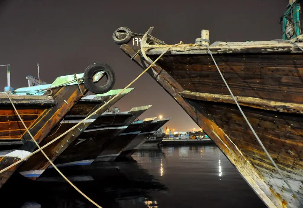 Wooden cargo dhows moored side by side on Dubai Creek at night