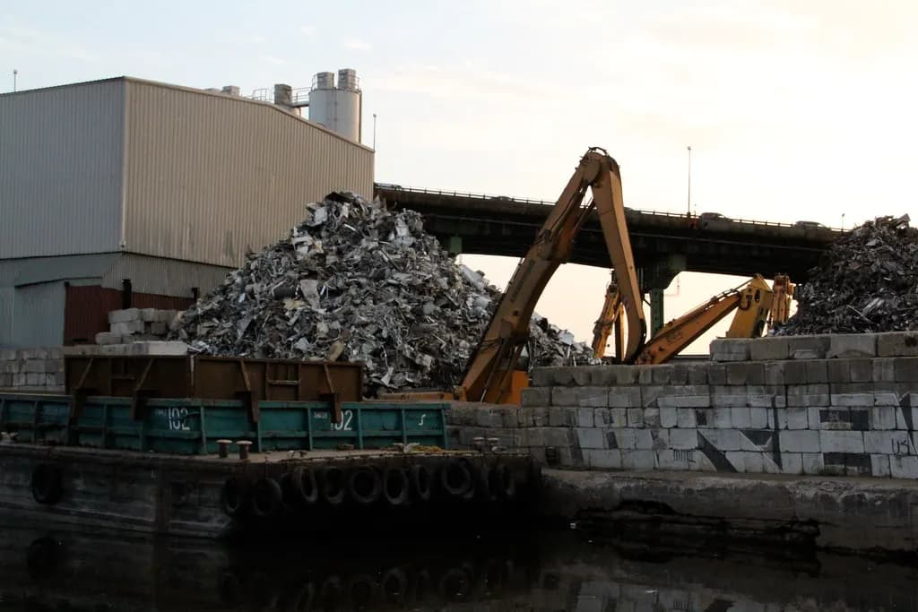 Piles of scrap metal and excavator grabs at a waterside scrap yard