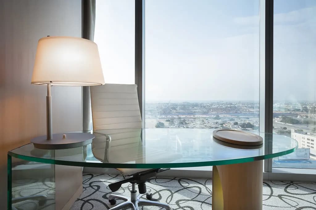 A glass desk and office chair by a window overlooking Dubai