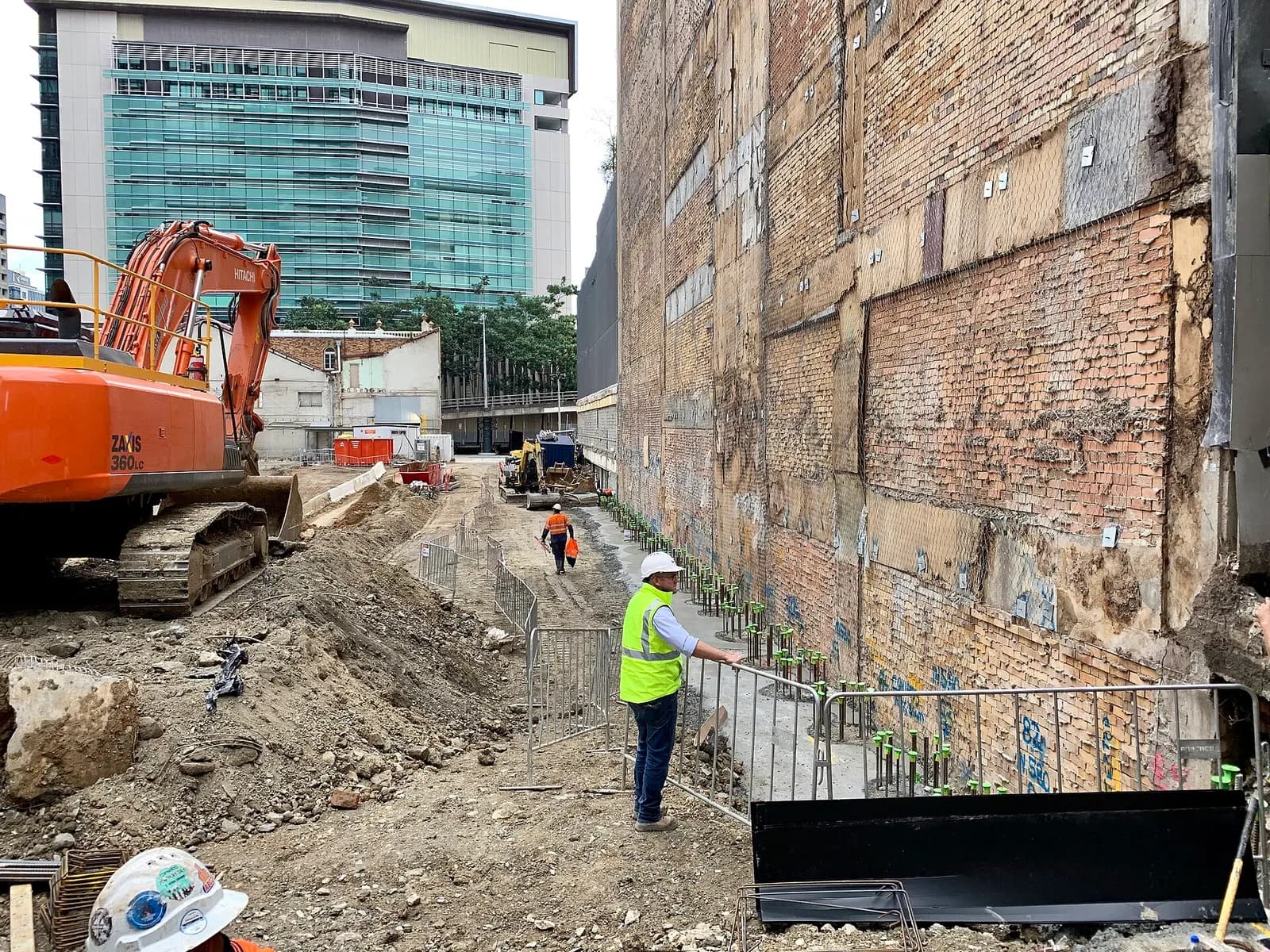 Excavator and a worker in high-visibility clothing on a city construction site at Ann Street, Brisbane