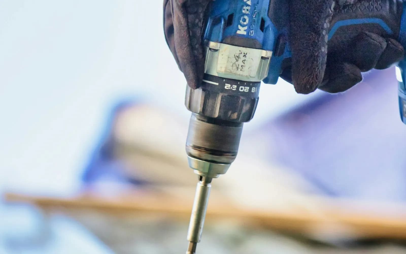 Contractor driving a screw into roof sheeting with a cordless drill