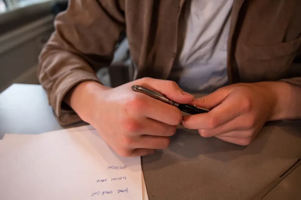 A person at a desk holding a pen over printed paperwork