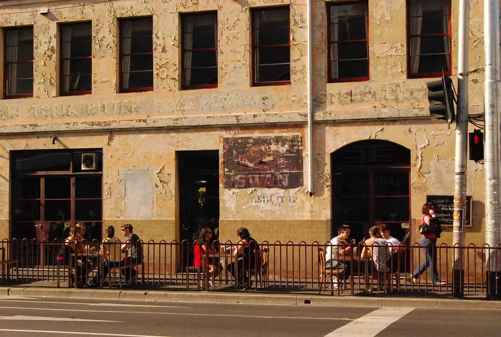 Customers at outdoor tables outside an old two-storey cafe building on a Melbourne street