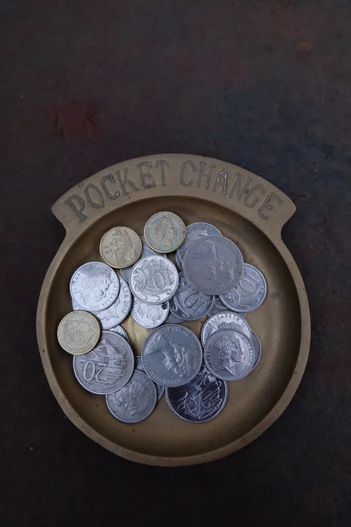 A brass dish labelled Pocket Change holding a mix of Australian coins