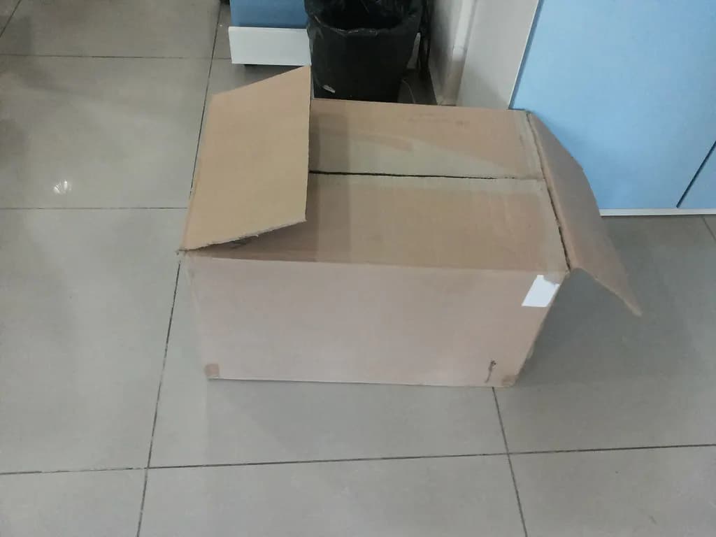 An open cardboard box on a tiled office floor