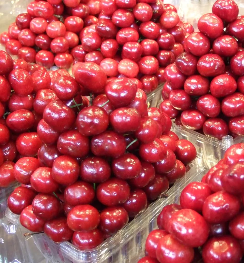 Crates of fresh cherries piled high at a produce stall in Granville Island Public Market, Vancouver