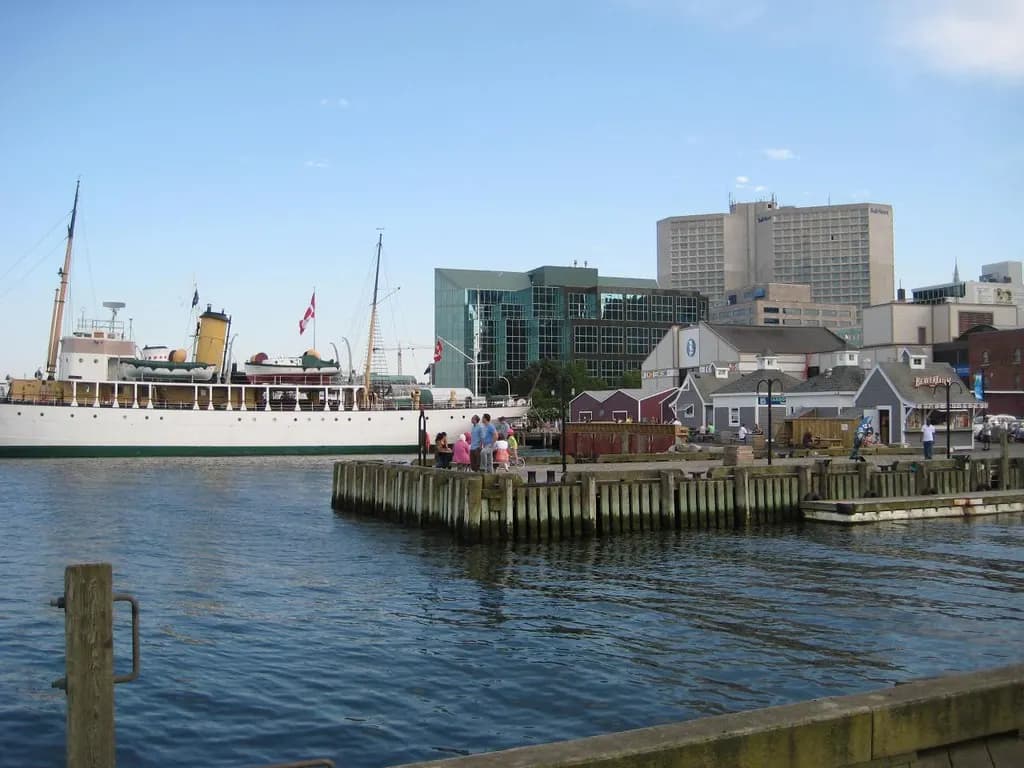The Halifax waterfront boardwalk with a moored white ship and harbourfront buildings under a blue sky