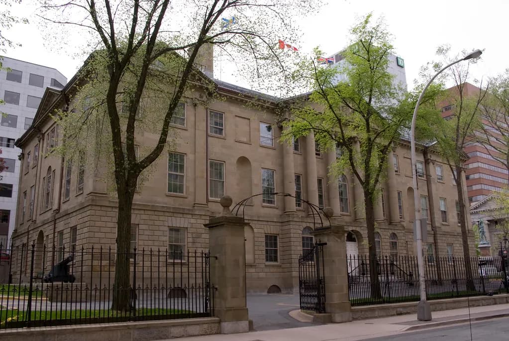 Province House, the sandstone home of the Nova Scotia Legislature, behind iron railings on a spring day in Halifax