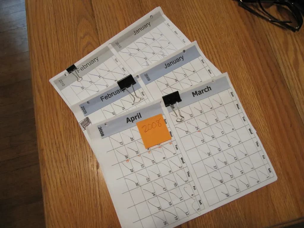 Printed monthly calendar pages for January to April clipped together on a wooden table