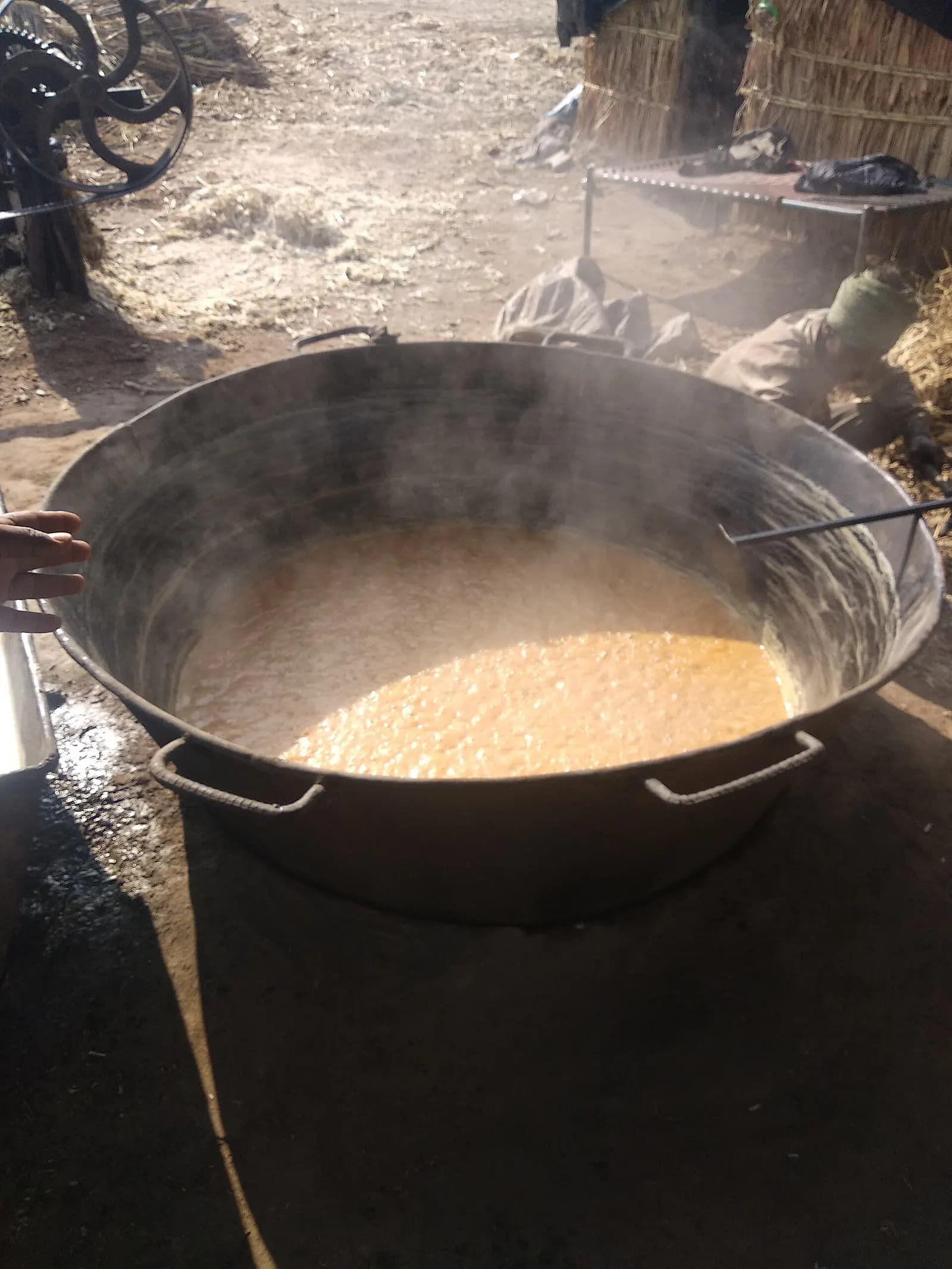 Sugarcane juice boiling into jaggery in a large iron pan at a village jaggery unit in India