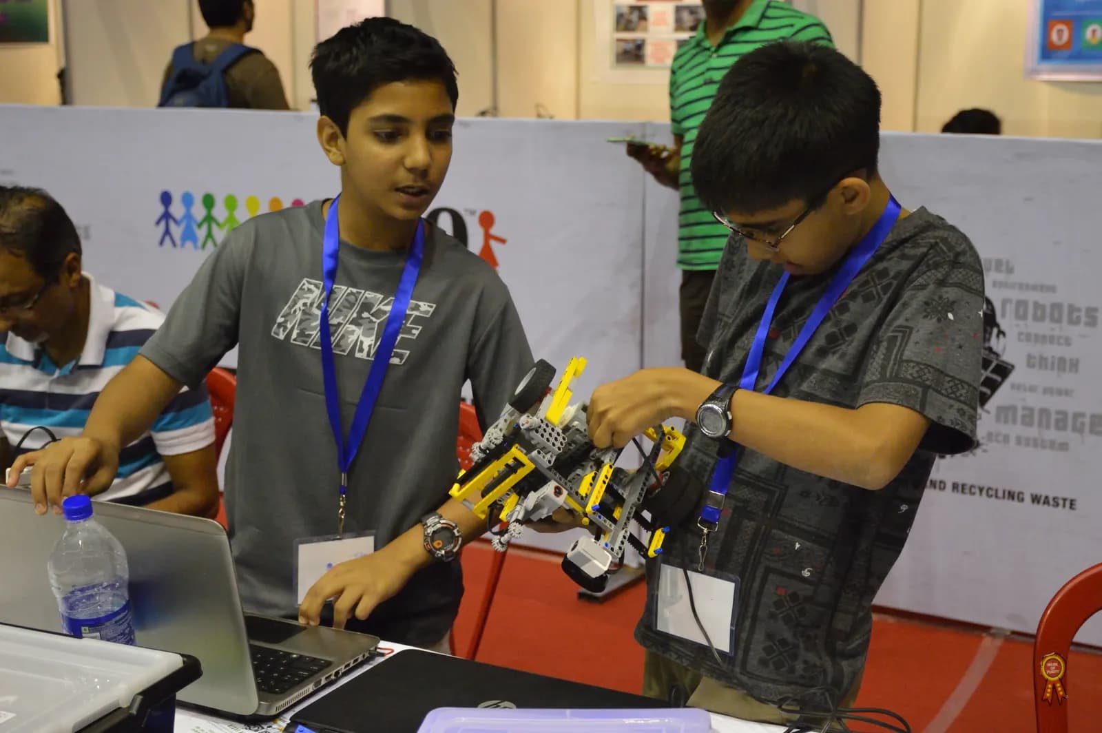 Two school students assembling and testing a robot at a robotics championship in Kolkata