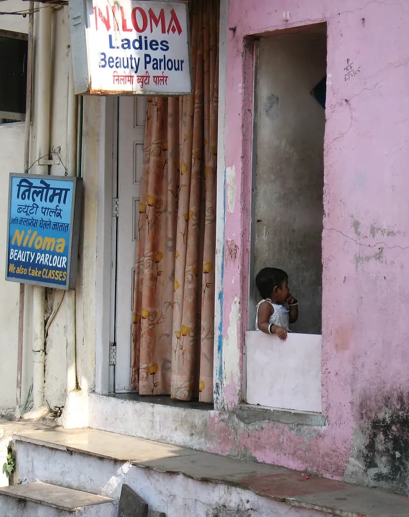 Entrance of a small ladies beauty parlour in India with hand-painted bilingual signboards in English and Hindi above a curtained doorway