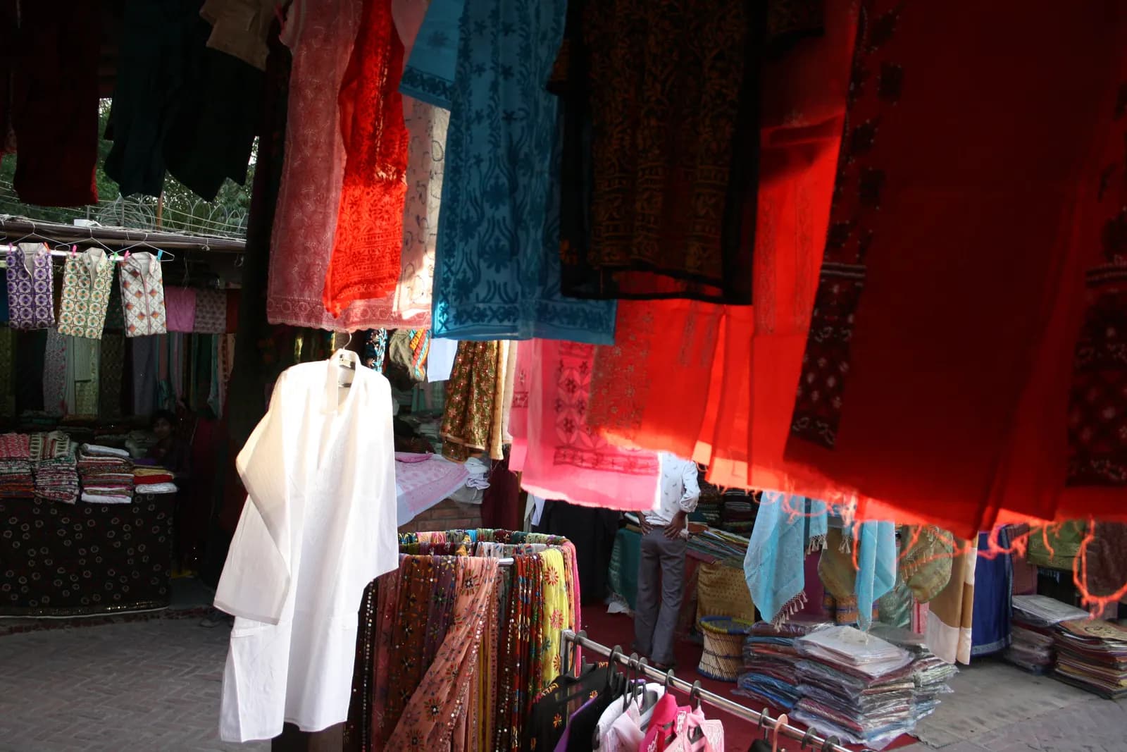 Embroidered kurtas and dupattas hanging on display at a stall in Dilli Haat, New Delhi