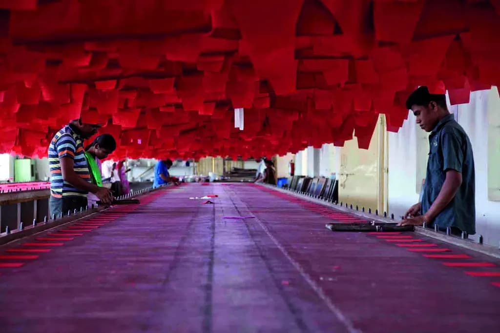 Workers printing fabric on long tables in a garment unit in Tiruppur, Tamil Nadu