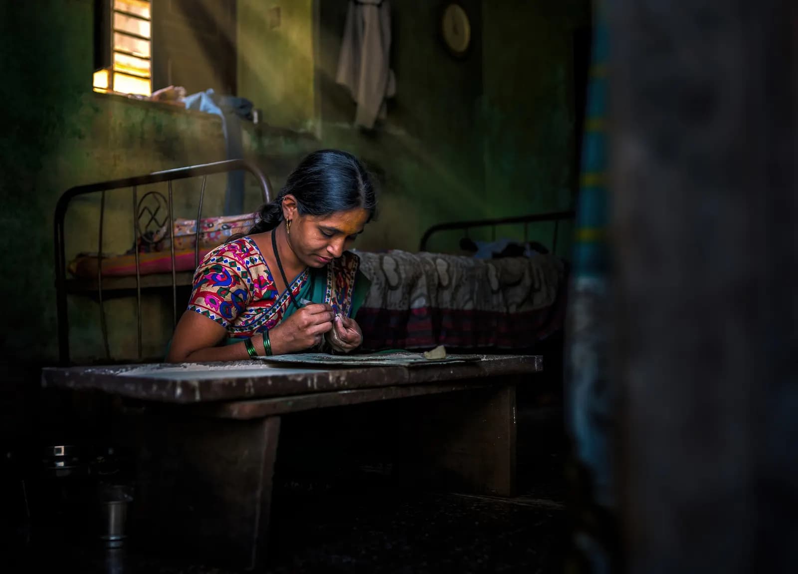Woman doing jewellery work by hand at a low table in a home workshop