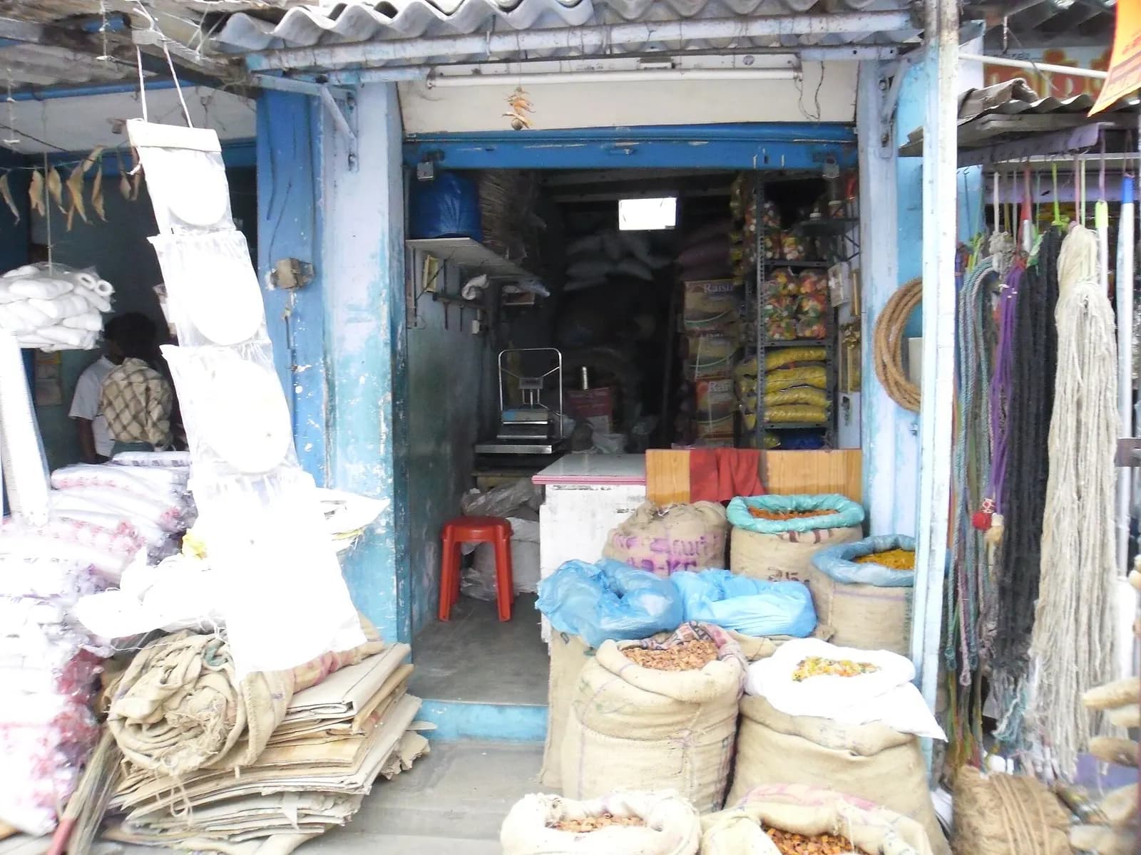 A small grocery and provisions shop in Salem, Tamil Nadu, with sacks of grains and spices at the front and shelves of packed goods inside
