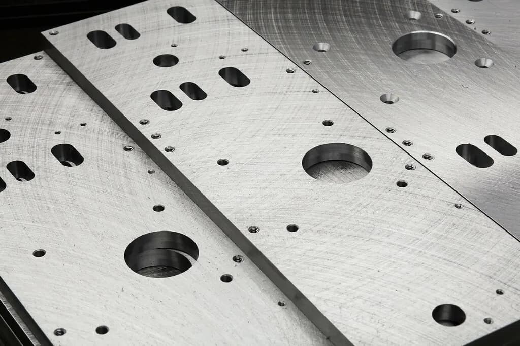 Close-up of precision CNC-machined aluminium plates with drilled holes and slots