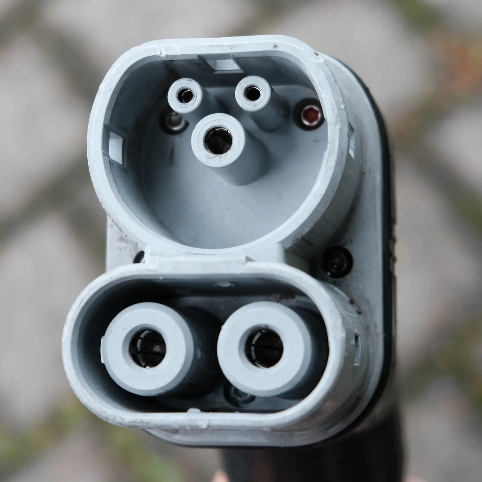Close-up of a CCS2 (Type 2 Combo) DC charging plug showing the AC pins above and two large DC pins below