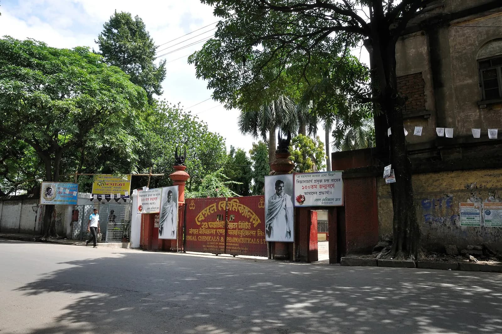 The gate of the Bengal Chemicals and Pharmaceuticals factory on a tree-lined street in Kolkata