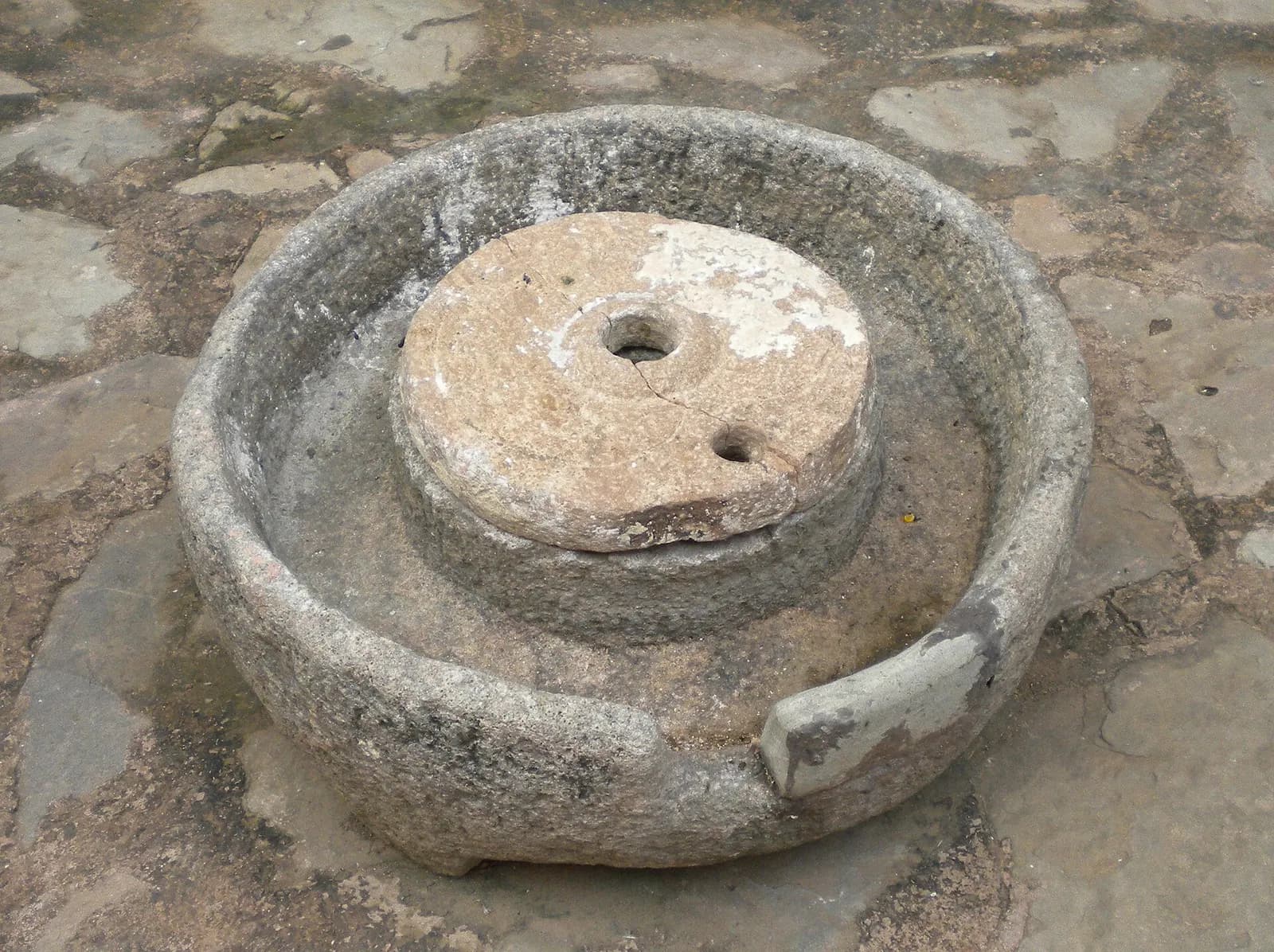 A traditional hand-turned stone chakki (quern) set in a round stone basin