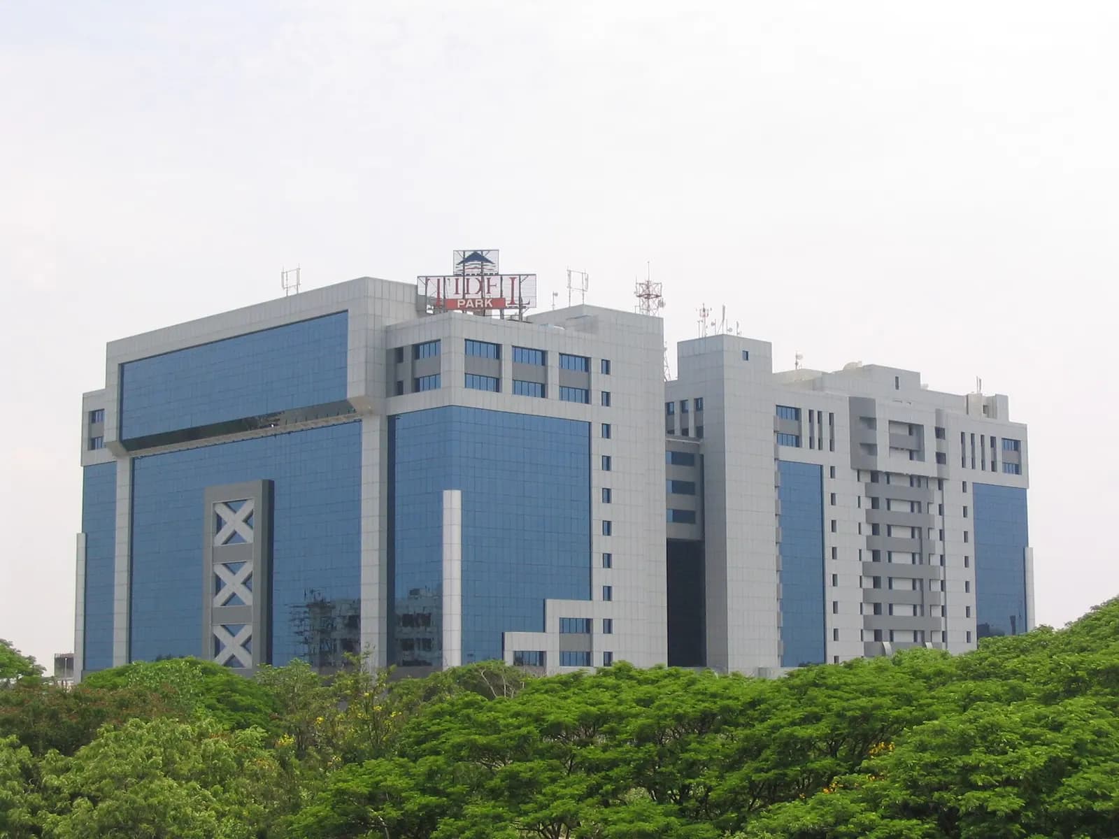 Blue glass office blocks of Tidel Park in Chennai rising above trees