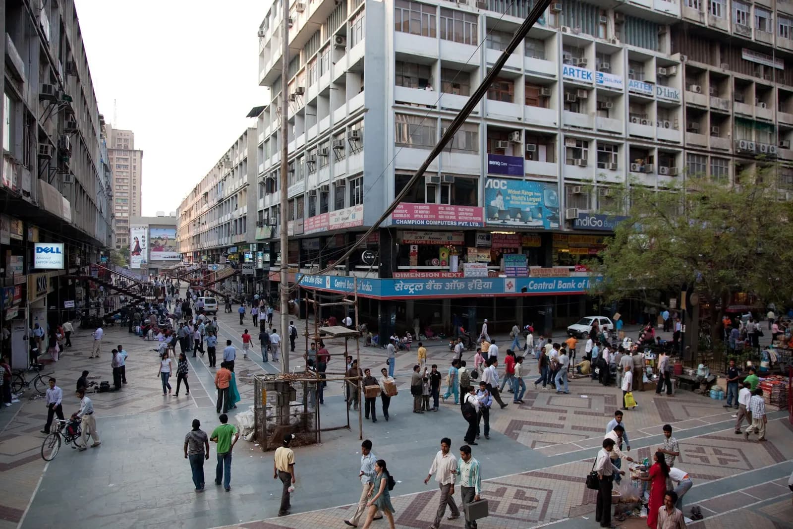 Shoppers and traders in the plaza of Nehru Place, New Delhi's computer and IT hardware market, with dealer signboards on office blocks