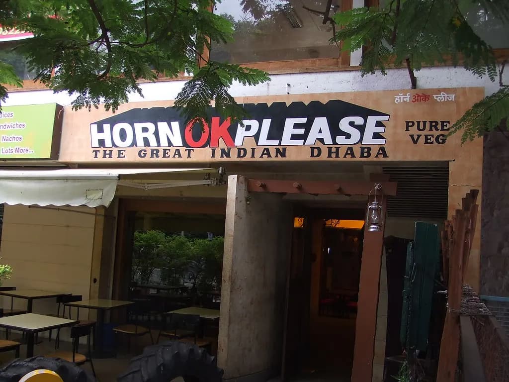 Entrance of a pure-veg dhaba-style restaurant in Pune with outdoor tables under trees