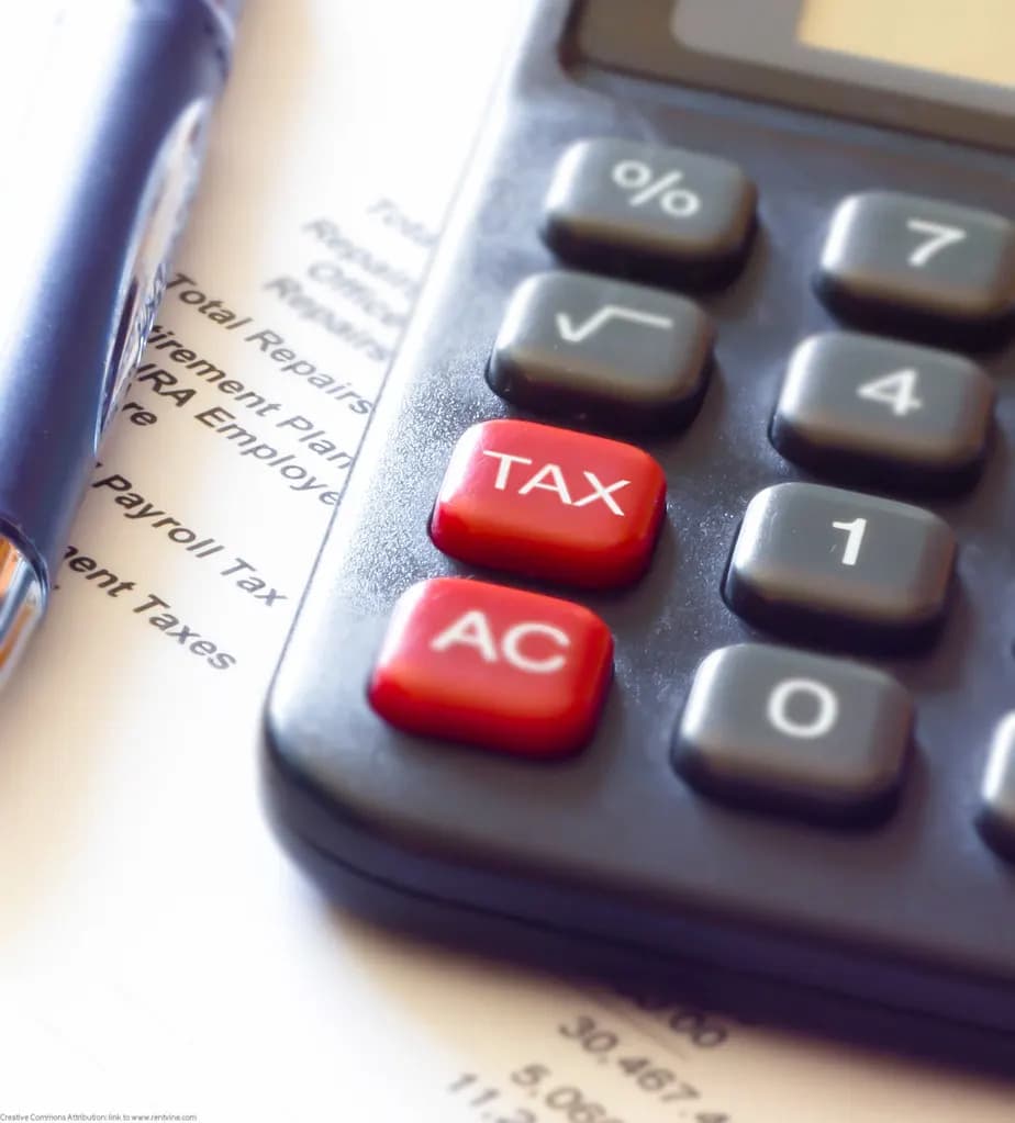 Close-up of a calculator with red TAX and AC keys resting on a printed tax form