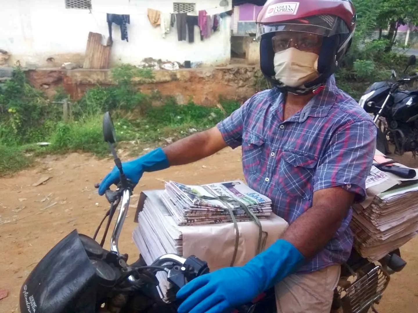 A newspaper vendor on a motorcycle carrying bundles of daily newspapers for delivery in India