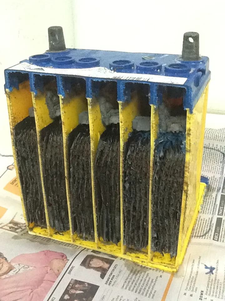 Cut-away view of a lead-acid car battery showing its plates and six cell compartments