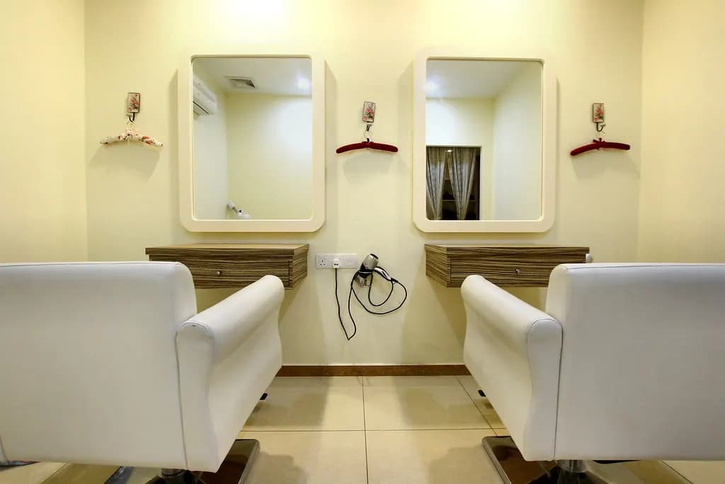 Two empty styling chairs facing wall mirrors with hair dryers in a beauty salon
