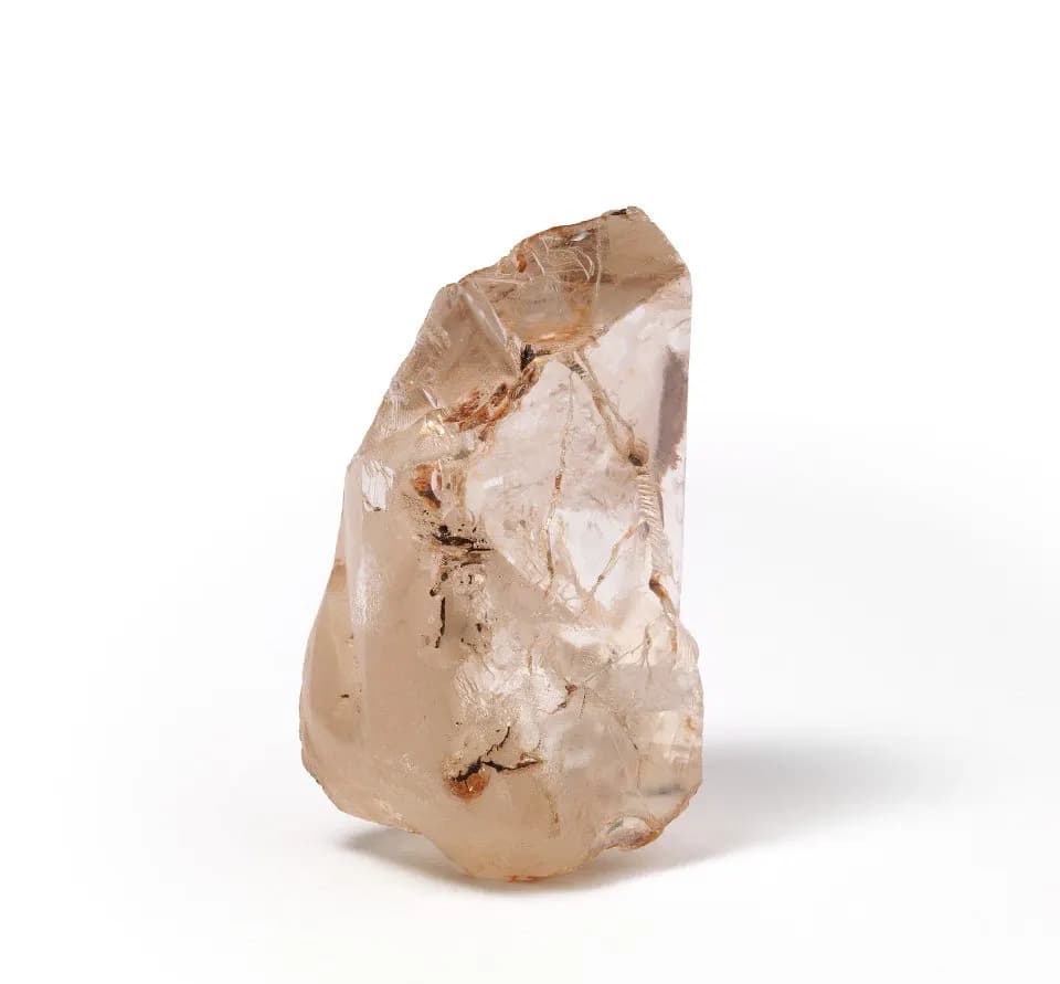 A single uncut rough diamond with a frosted, pale pinkish surface against a white background