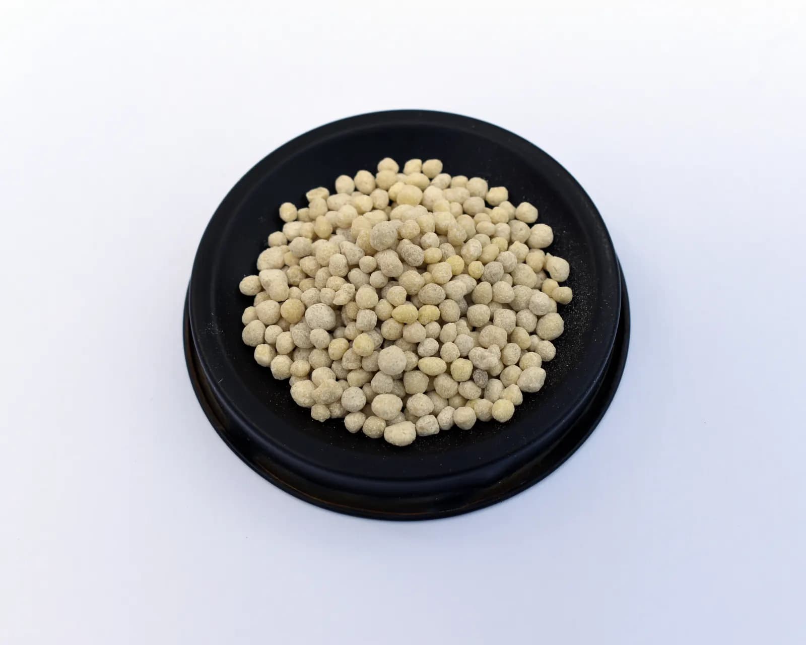 A small black dish filled with cream-coloured granules of diammonium phosphate fertiliser