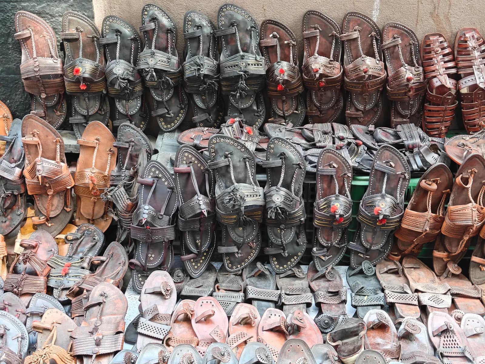 Rows of handmade leather Kolhapuri chappals stacked for sale at a roadside stall in Kolhapur