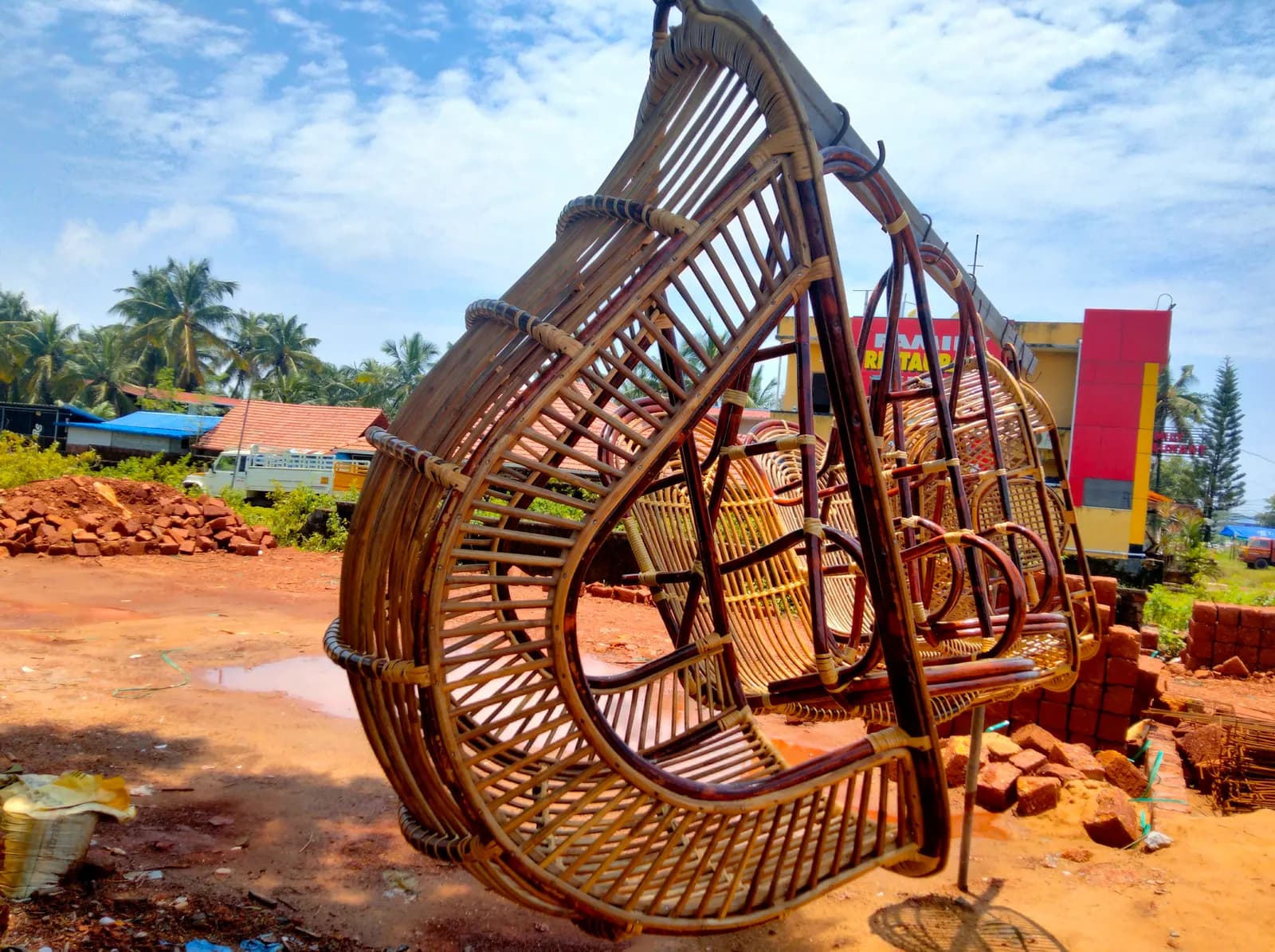 Handmade cane swing chairs hanging for sale at a roadside workshop in India