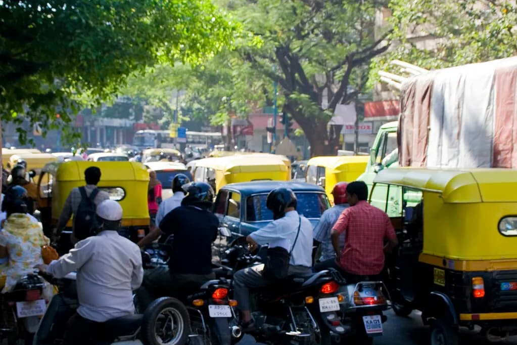Cars, auto-rickshaws and motorcycles queued in heavy traffic on a tree-lined road in Bangalore