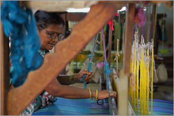 A weaver working coloured warp threads on a handloom in Maheshwar, Madhya Pradesh