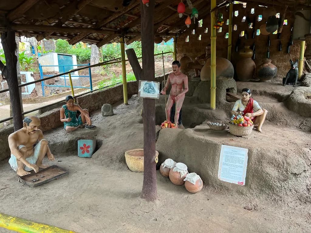 Museum diorama of a traditional feni distilling unit in Goa with clay pots, cashew apples and figures of workers