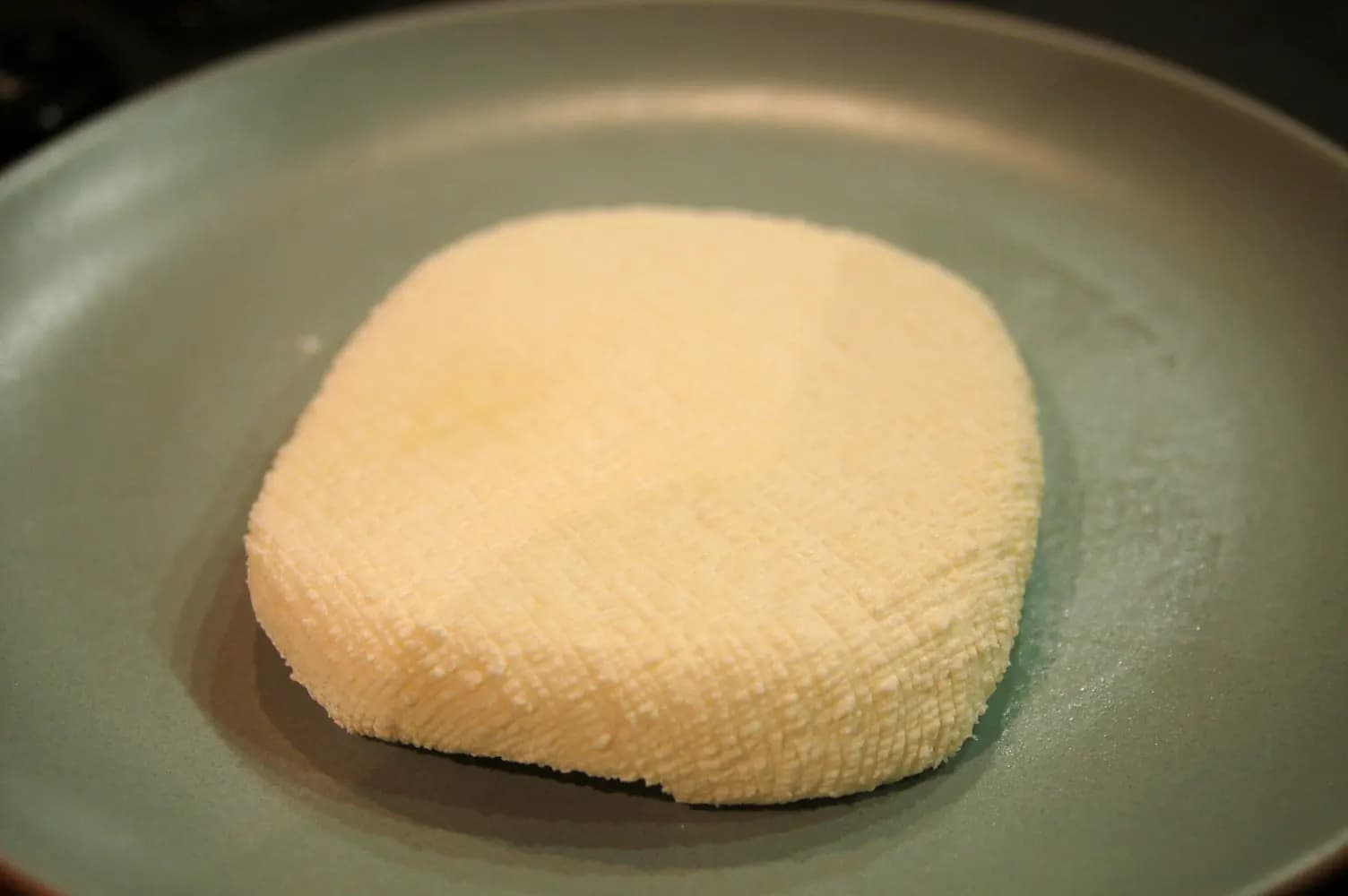 A freshly pressed block of paneer in a pan