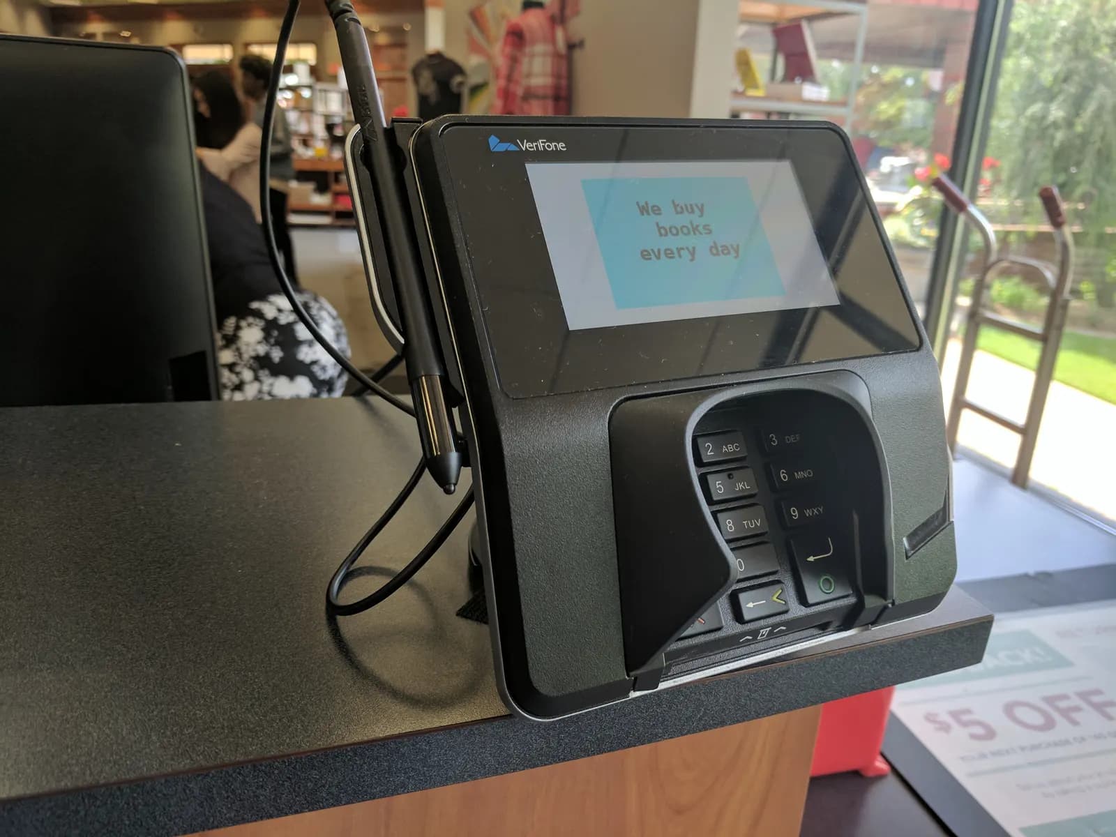 A card payment terminal with a stylus on a shop counter