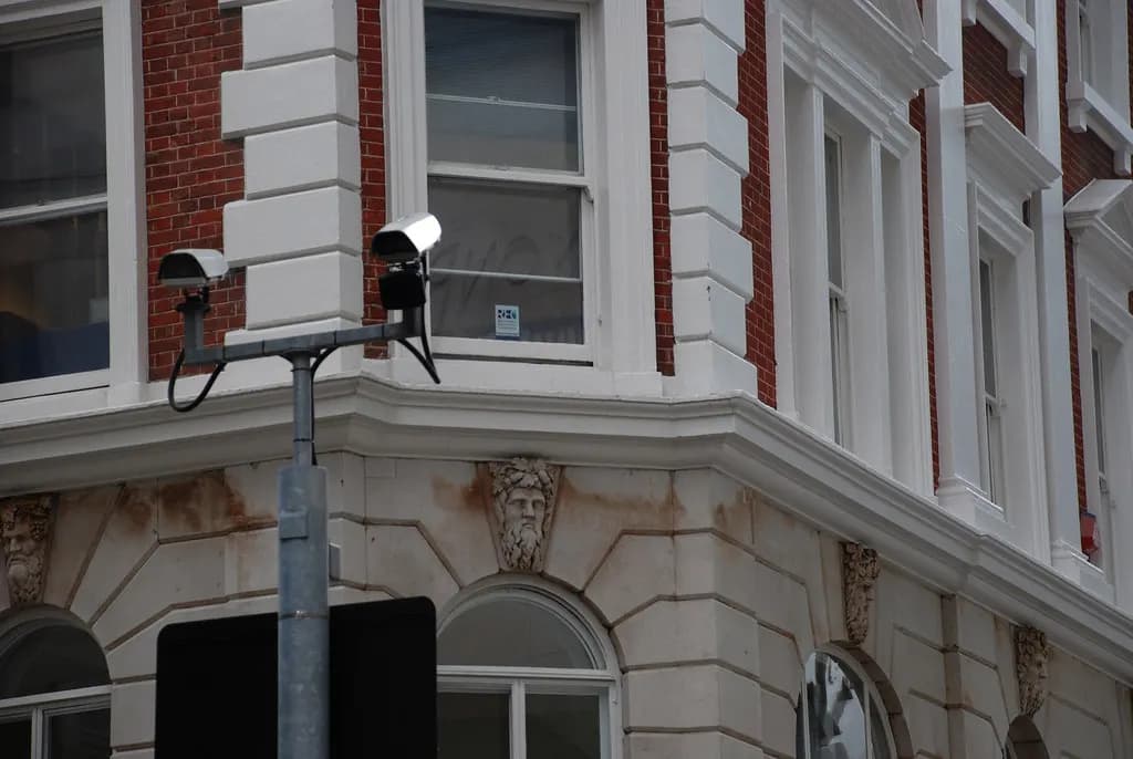 Two CCTV cameras mounted on a pole outside a brick and stone building