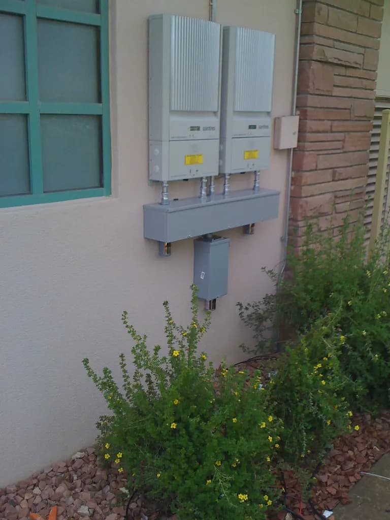 Two grid-tie solar inverters and a junction box mounted on an outside wall