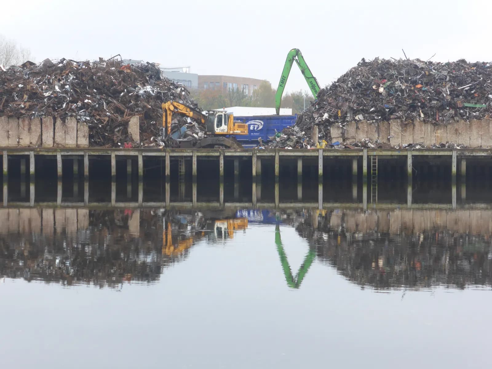 Large heaps of ferrous scrap at a waterside scrap yard with material-handling cranes