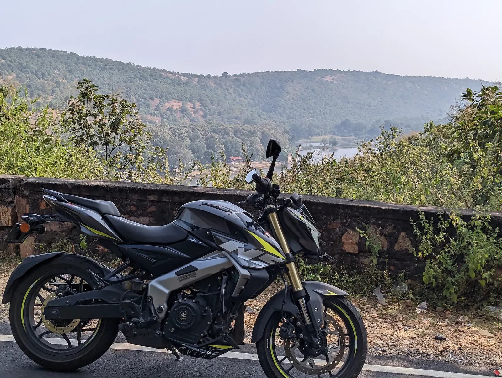 A naked-street motorcycle with a 373 cc engine parked on a hill road beside a stone wall
