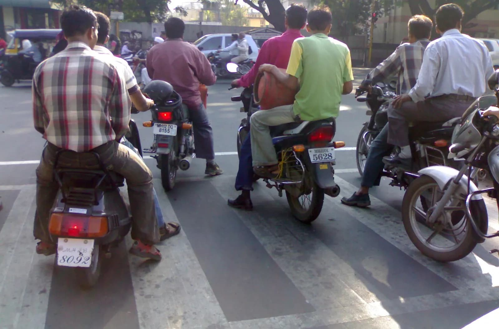 Riders on motorcycles and scooters waiting at a zebra crossing in Pune traffic