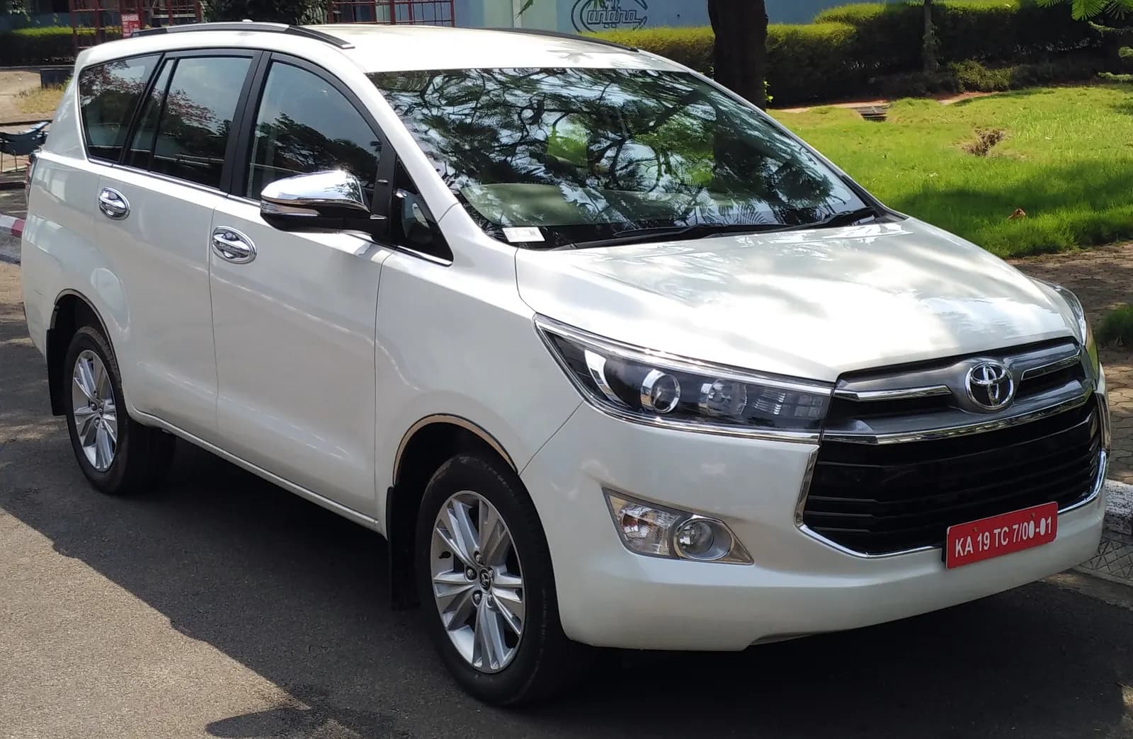 A white seven-seat multi-purpose vehicle of the kind widely hired with a driver for corporate and tourist trips in India