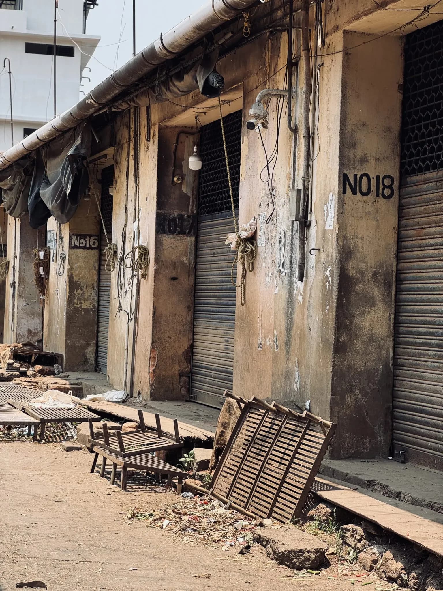 Row of closed shops with rolling metal shutters and peeling walls at Palayam market, Thiruvananthapuram