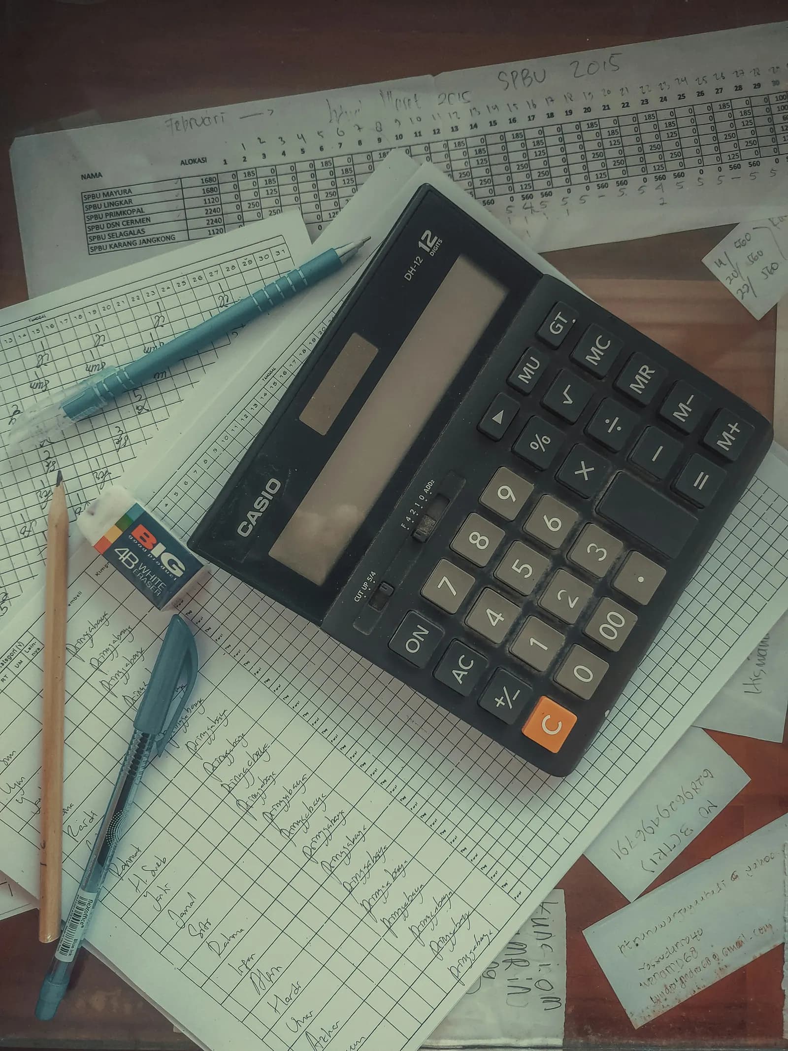 A calculator resting on a pile of printed invoices and papers